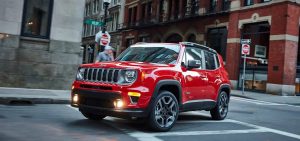 Red 2021 Jeep Renegade making a turn on city roads.