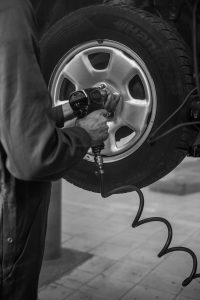 Gray scale image of a person working on a tire.