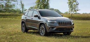 Dark grey Jeep Cherokee in a field of grass