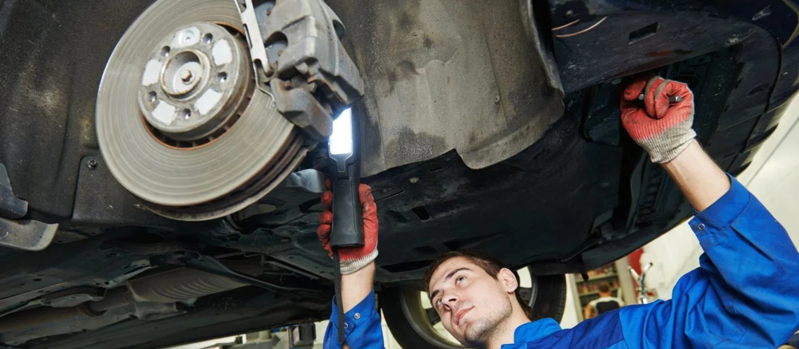 Technician performing brake service on a vehicle inside a professional dealership service center